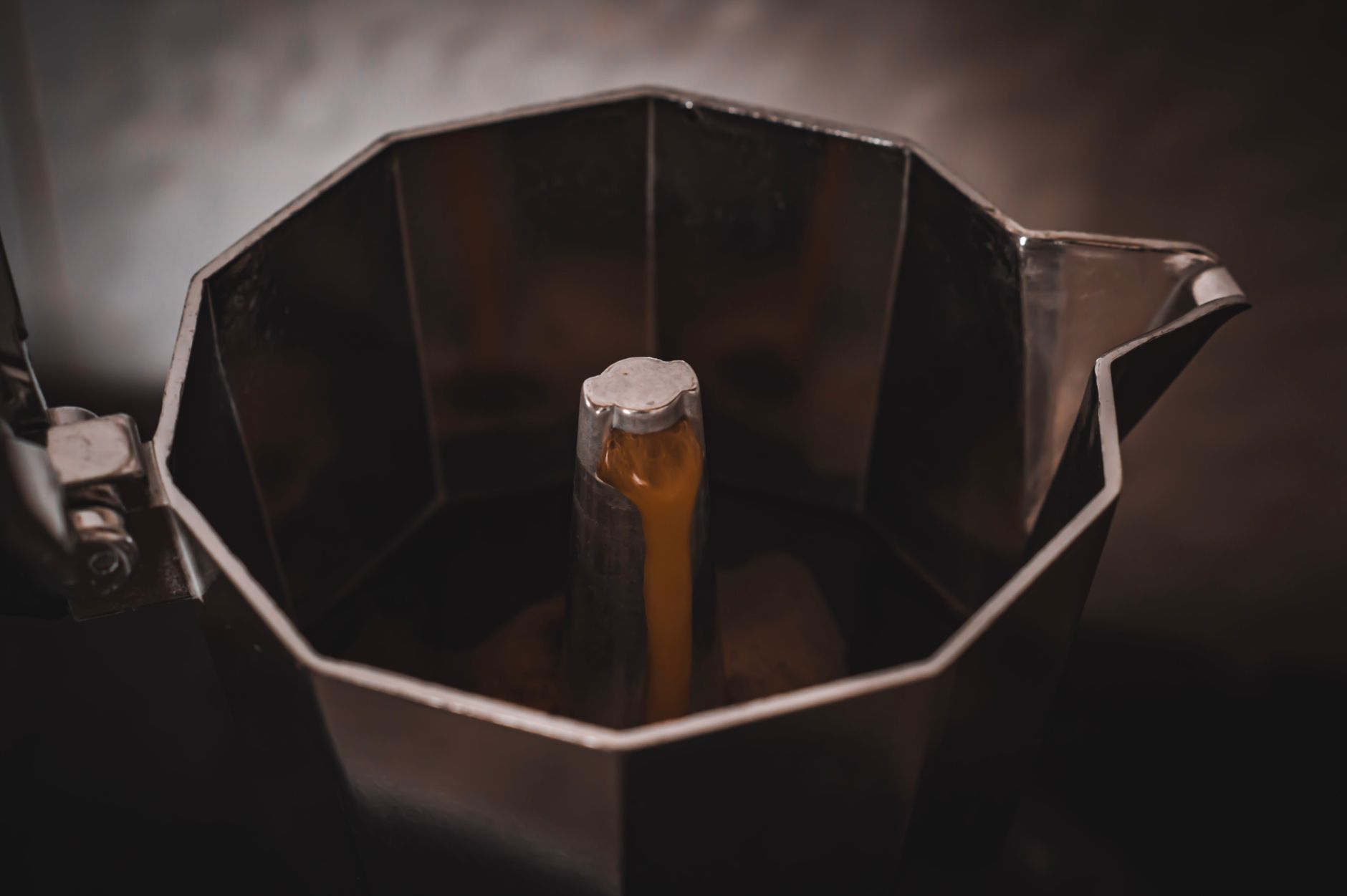 A detailed view of espresso brewing in a steel Moka pot, capturing rich coffee textures.