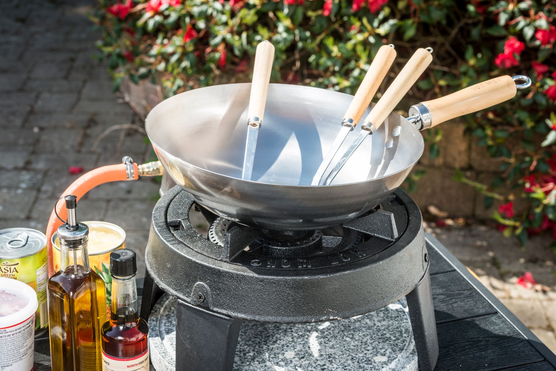An outdoor cooking station featuring a wok, utensils, and cooking ingredients.