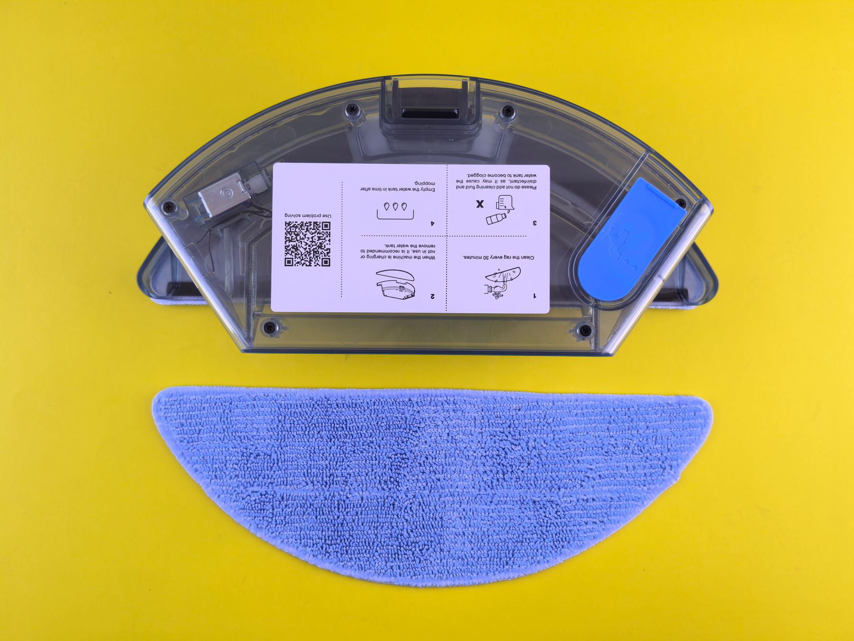 Cleaning robot water tank and mop on yellow backdrop, showcasing household appliance detail.