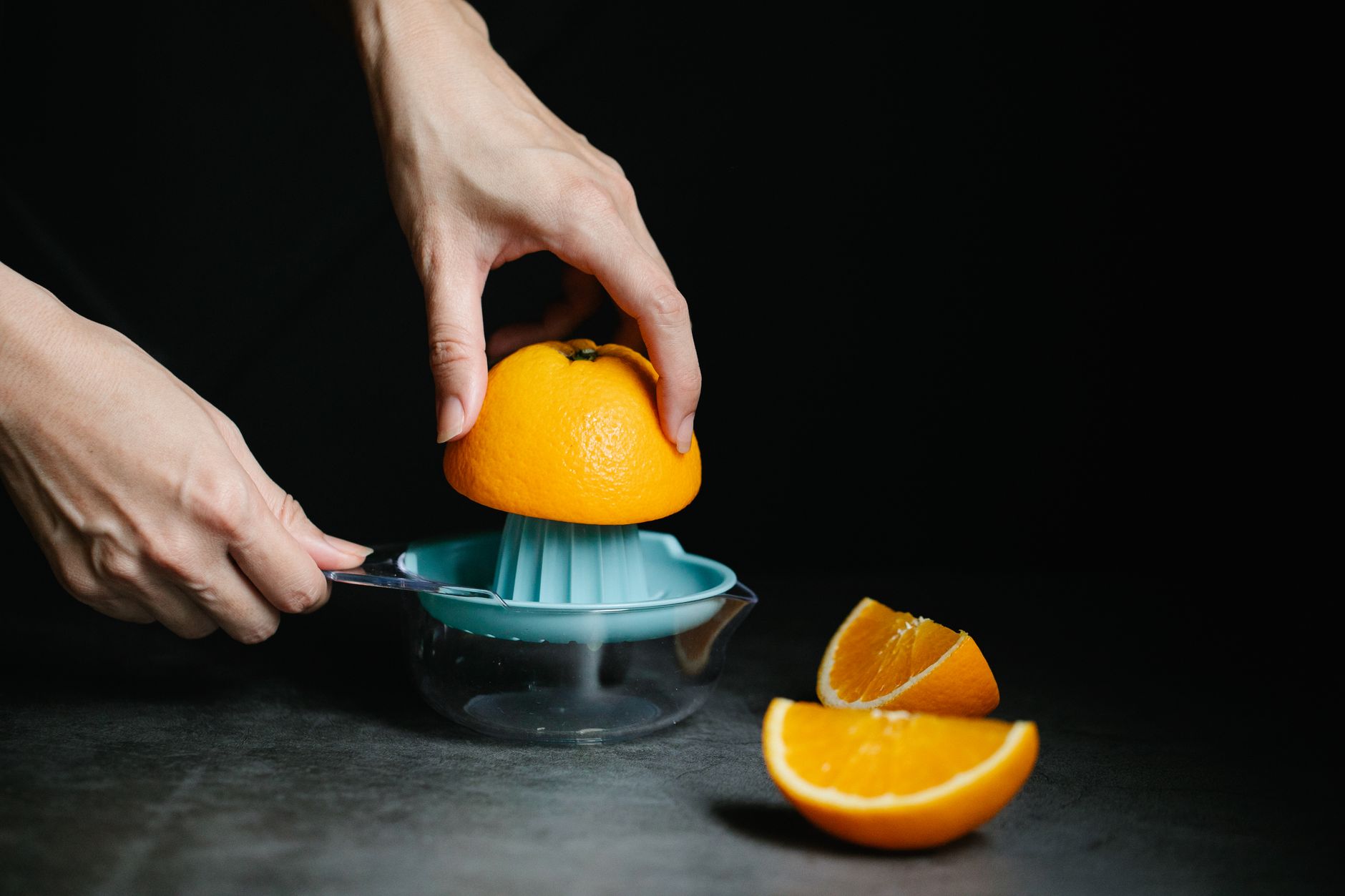 Close-up of hands squeezing orange juice with a manual juicer, capturing the freshness and vibrancy of citrus fruits.