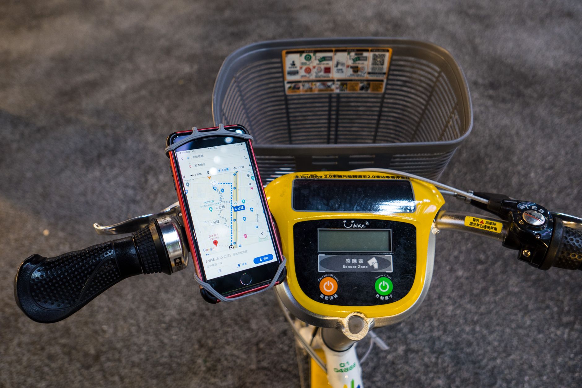 Smartphone displaying map navigation on a mounted electric bike handlebar with control panel.