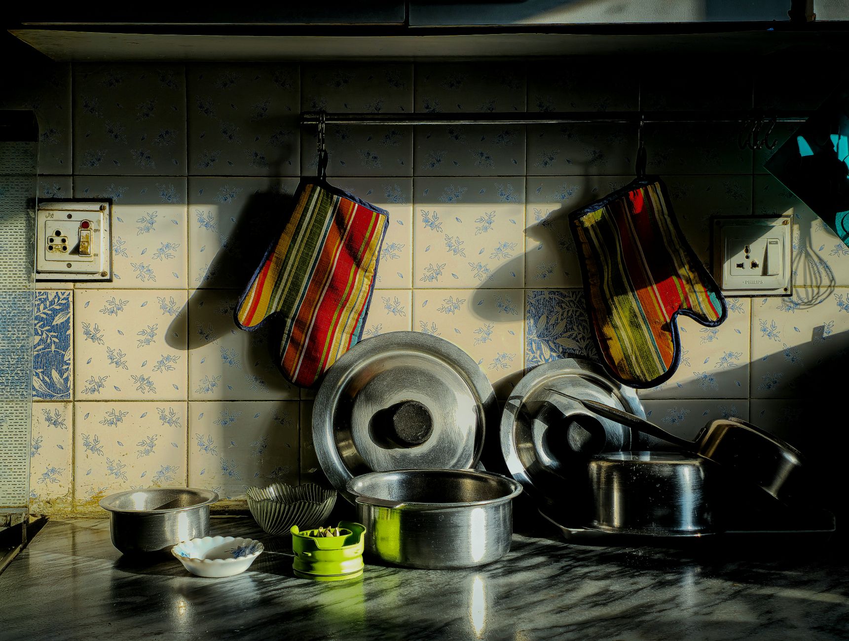 A warm kitchen setting with colorful oven mitts and stainless steel pots.