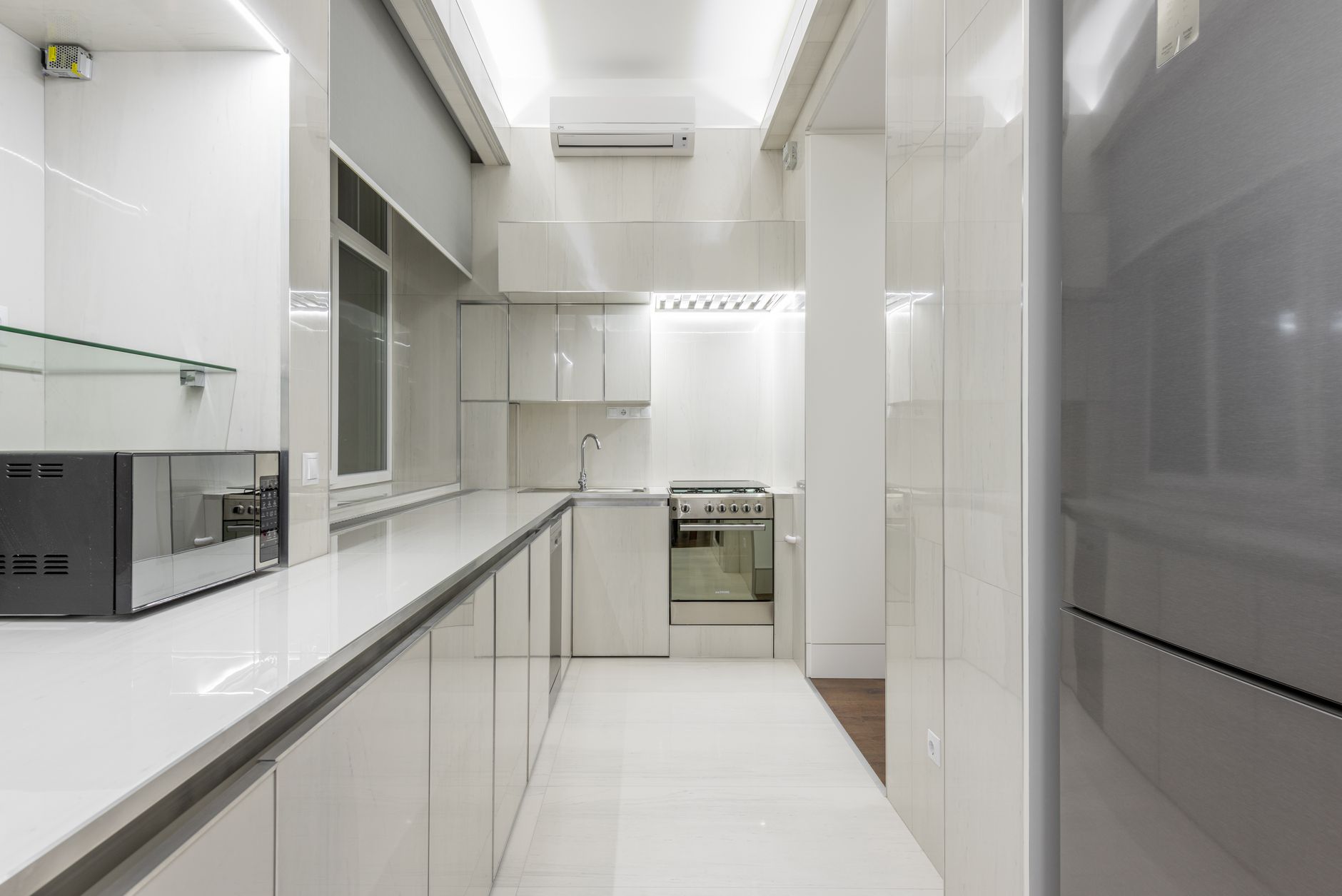 Bright, sleek kitchen showcasing modern minimalist design with white cabinetry and stainless steel appliances.