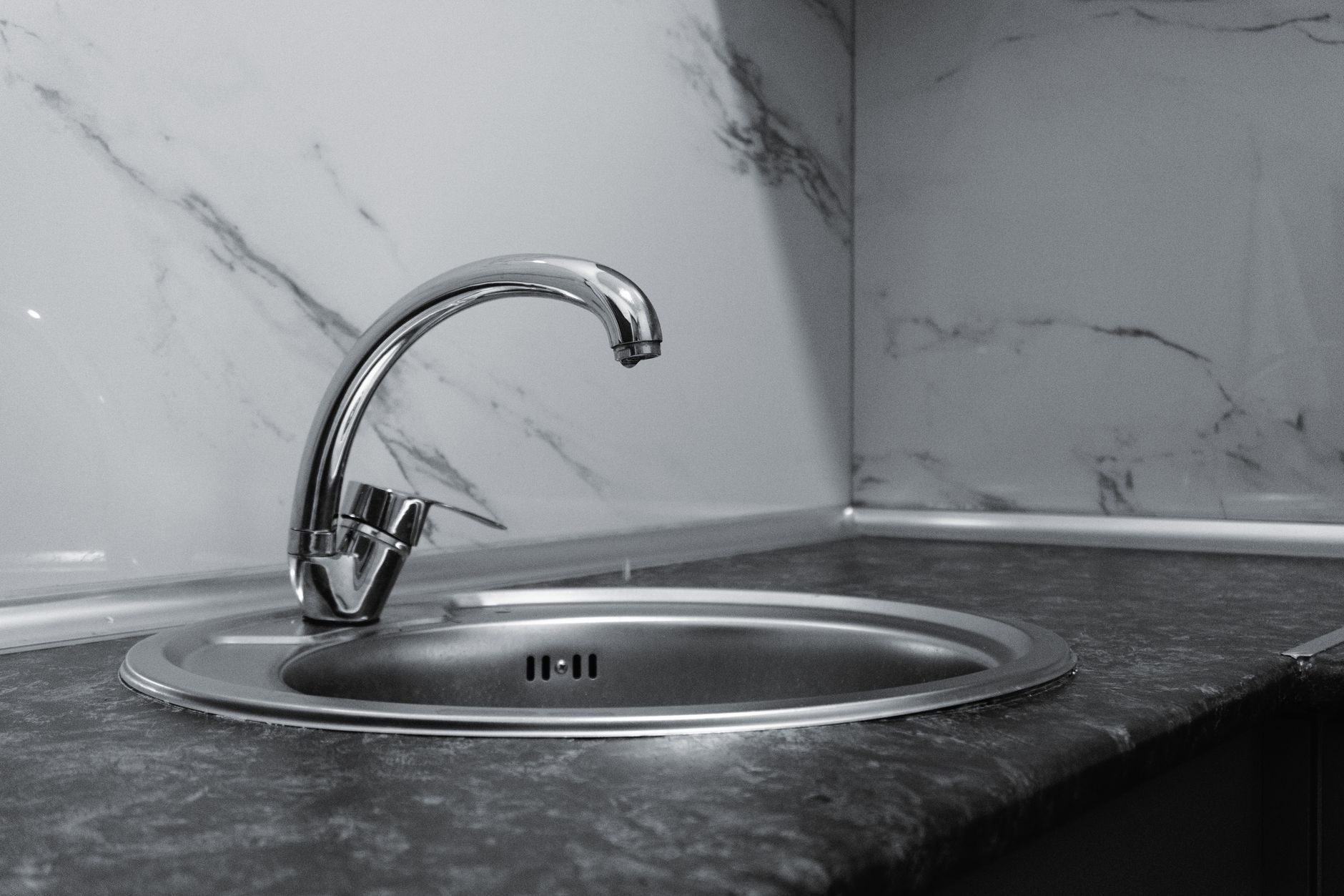 A stylish stainless steel kitchen faucet with a sleek and modern design set against a marble backsplash.