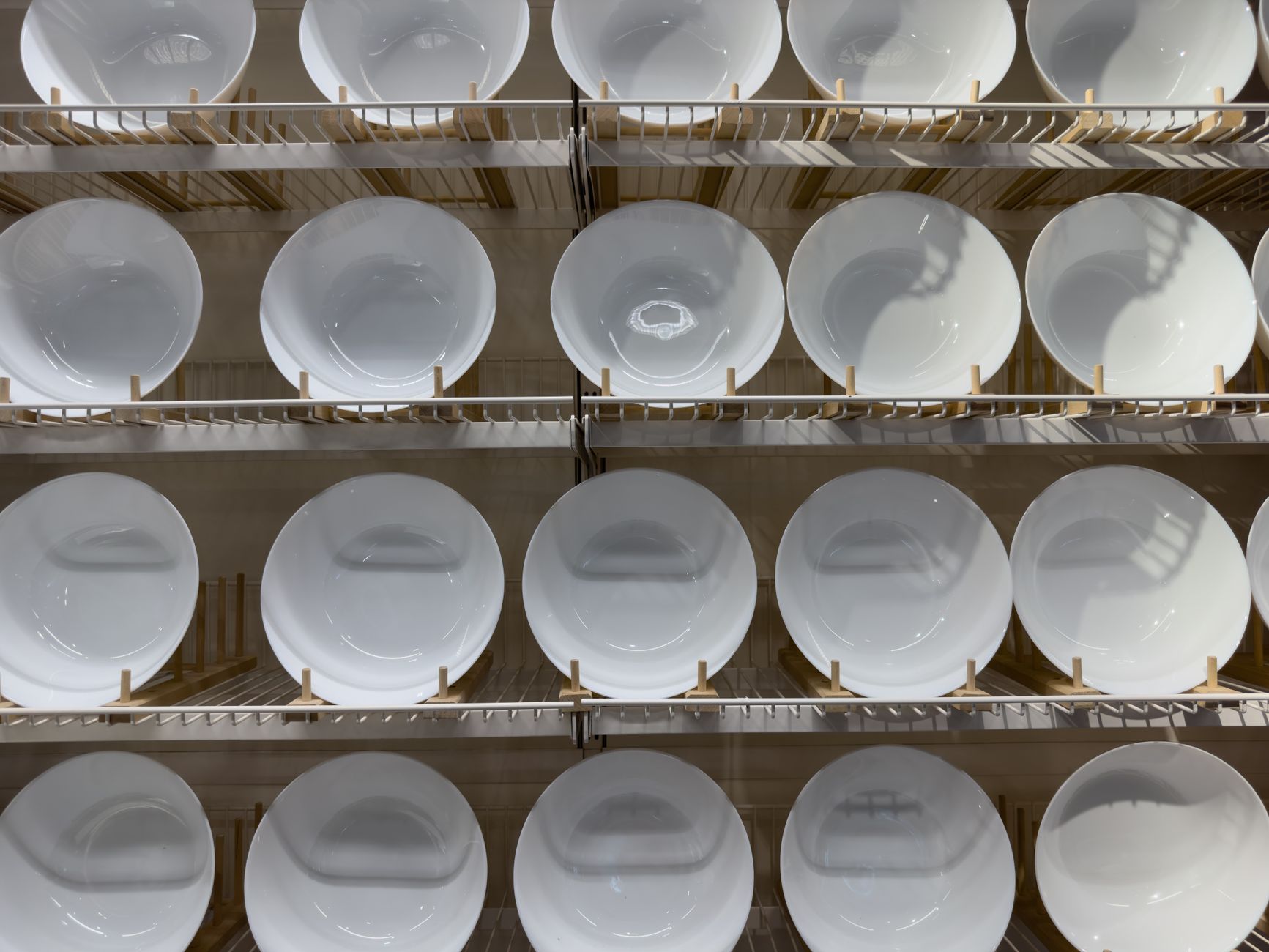 Artistic arrangement of white porcelain plates on shelves in a retail store, showcasing minimalist design.