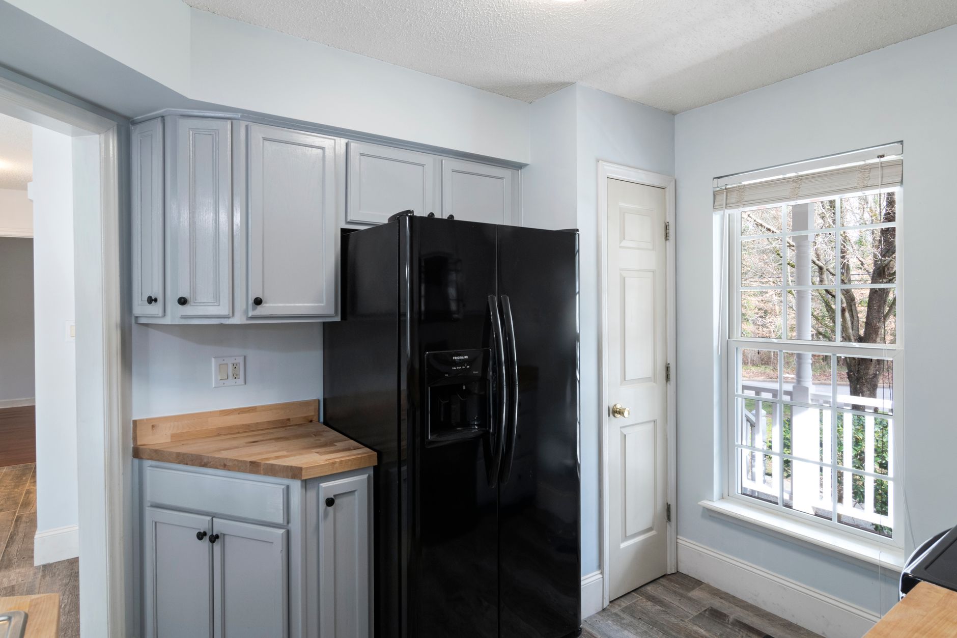 A modern kitchen featuring a sleek black refrigerator and large window.
