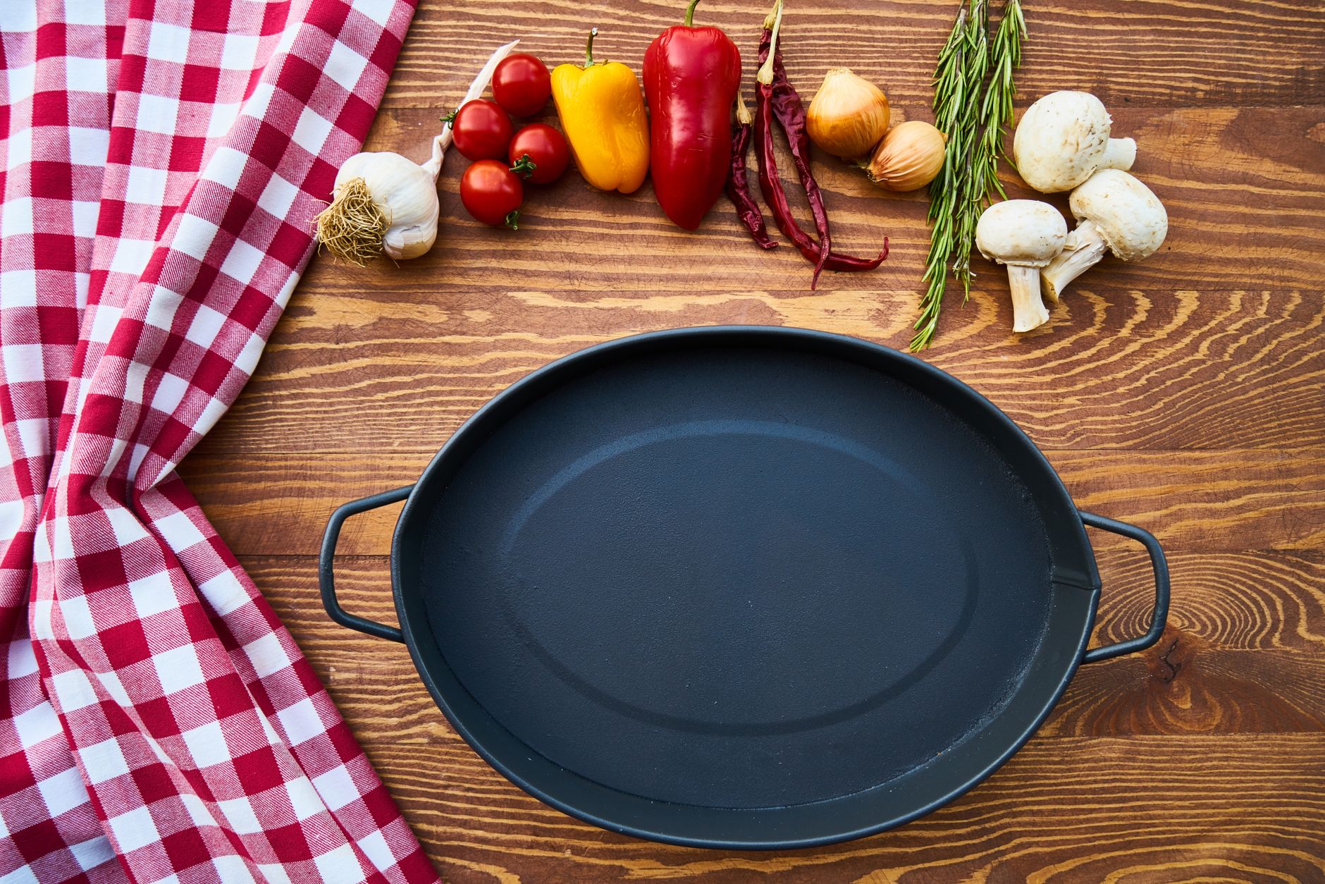 Empty cast iron pan with fresh ingredients on a wooden table.