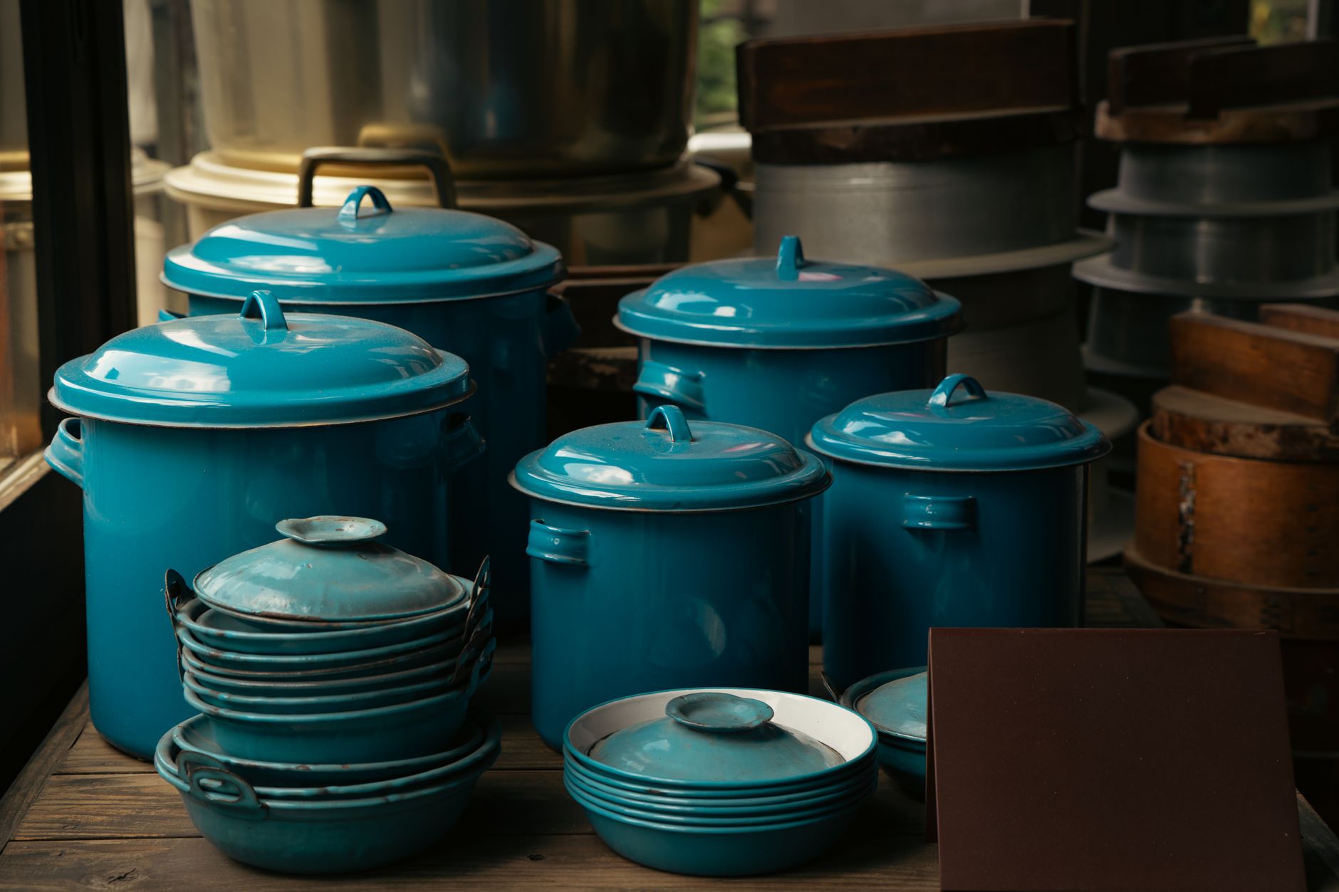 A collection of vintage blue enamel pots and dishes on wooden shelves in a traditional setting.