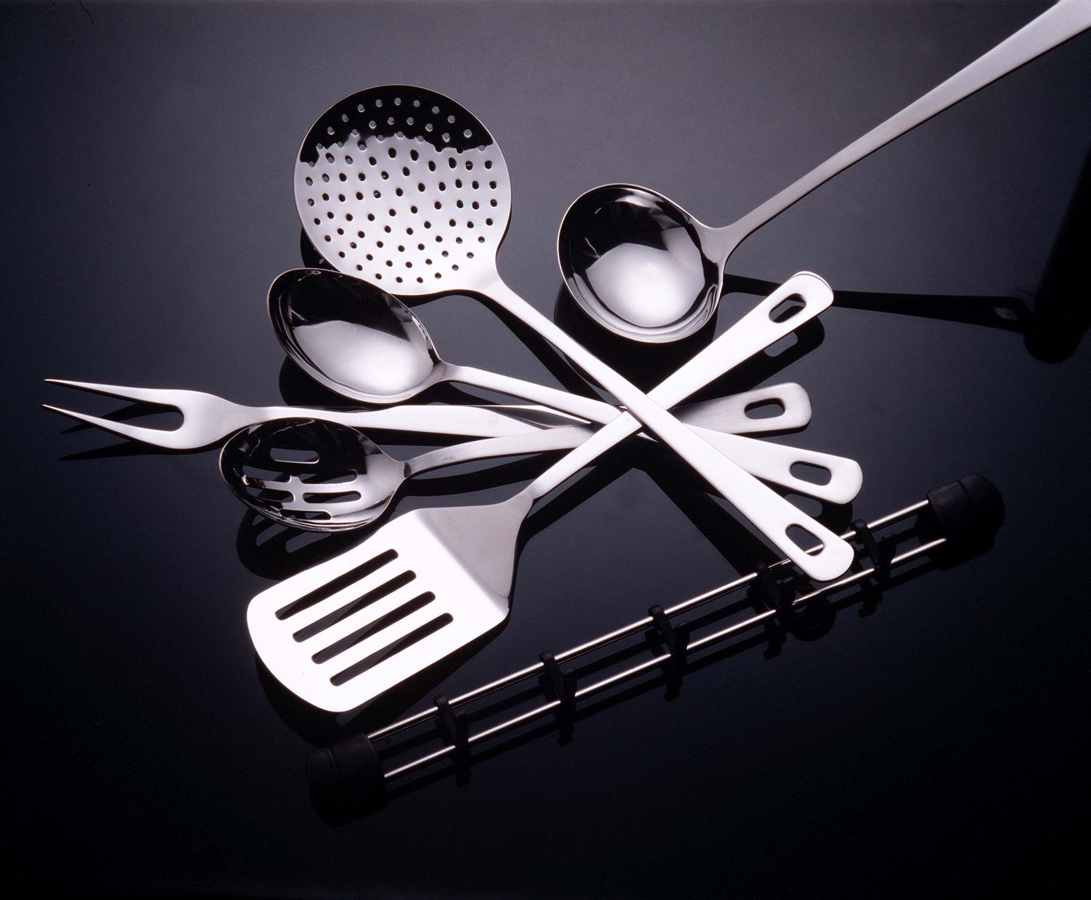 Collection of stainless steel kitchen utensils on a sleek black surface.